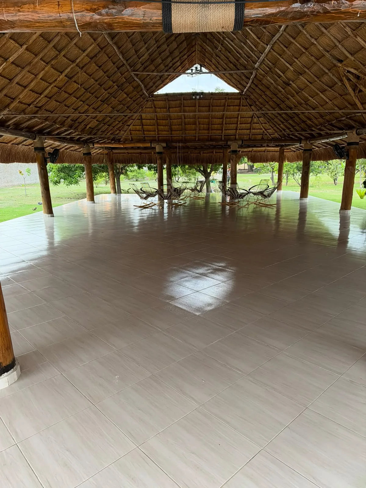 Interior abierto del kiosco con estructura de madera, techo de palma y hamacas